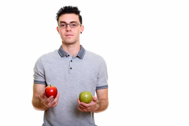 istock Studio shot of young man holding red and green apple 669187784