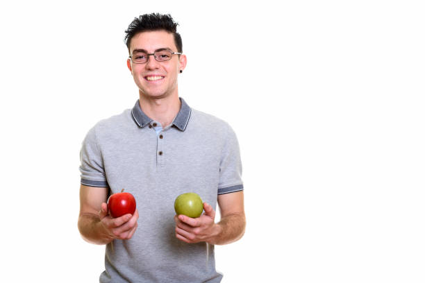 istock Studio shot of happy young man smiling while holding red and green apple 669187794