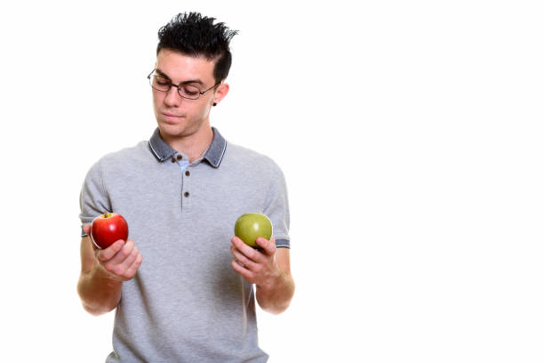 istock Studio shot of young man choosing between red apple and green apple 669187822