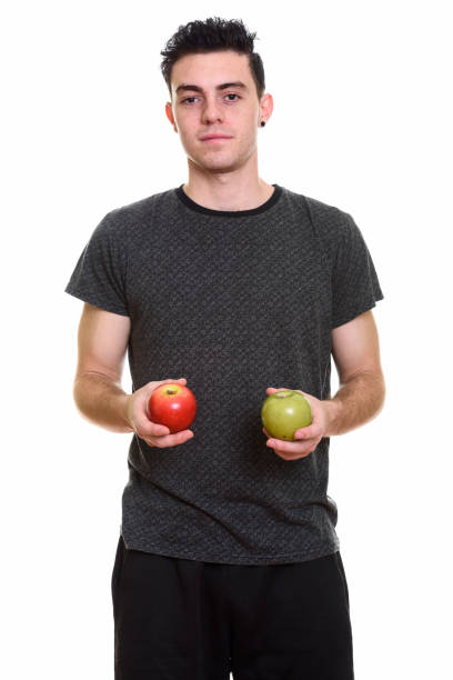 istock Studio shot of young man standing while holding red and green apple 669187862