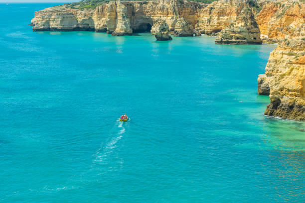 Touristic boat sailing on Algarve beautiful Atlantic coast and turwuoise waters.