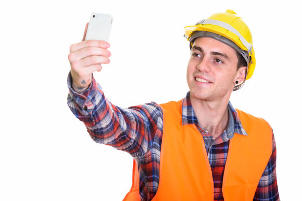 istock Close up of happy young man construction worker smiling while taking selfie with mobile phone 669191066