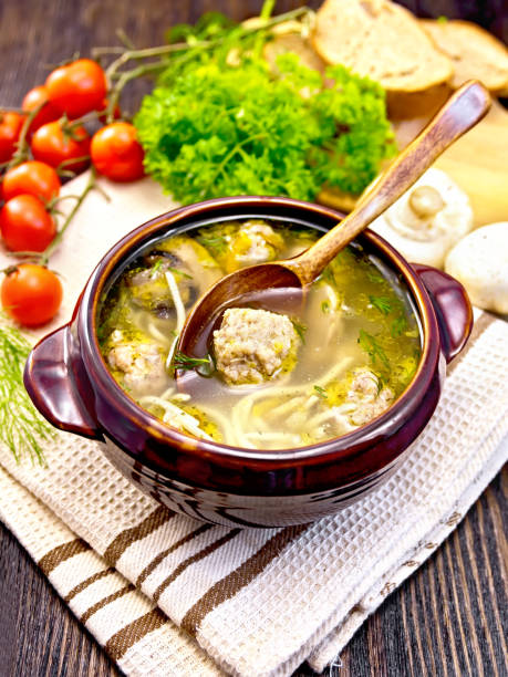 istock Soup with meatballs and spoon in clay bowl on dark board 669200780