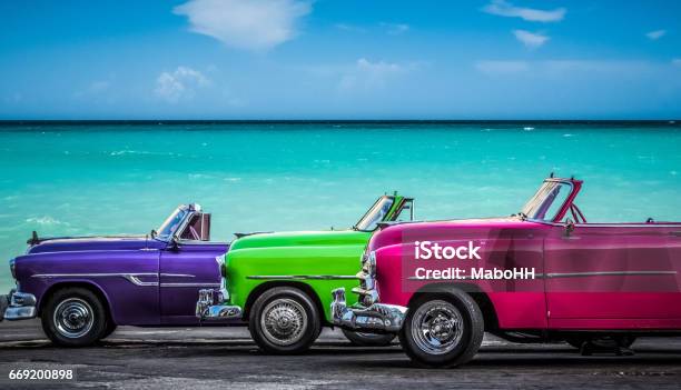 Three Colorfully Convertible Classic Cars Parked Before The Caribbean Sea On The Malecon In Havana Cuba Stock Photo - Download Image Now