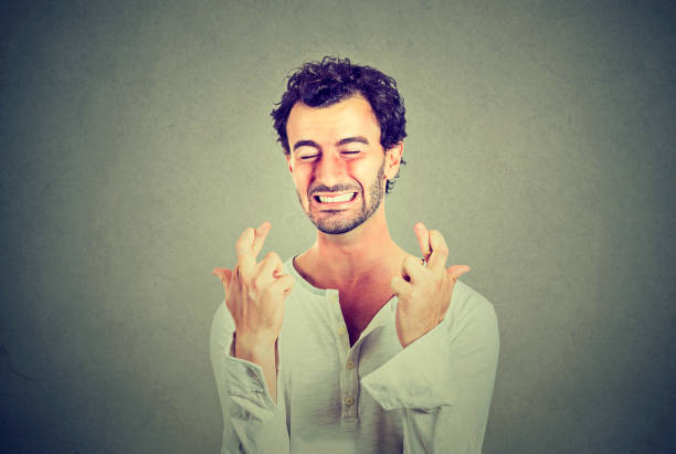 istock Hopeful handsome man crossing his fingers, eyes closed 669211028