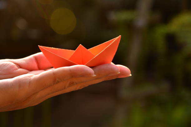 istock red paper ship on hand of human 669213900