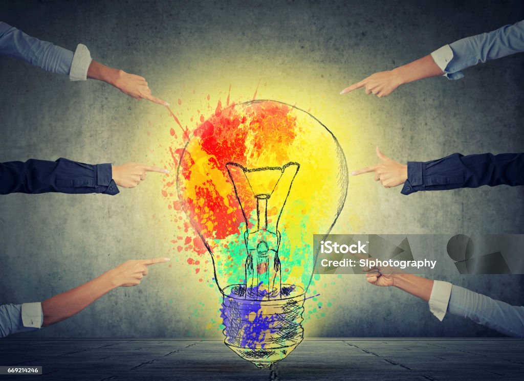 Human arms fingers point at bright idea colorful glowing light bulb Human arms fingers point at bright idea colorful glowing light bulb isolated on gray wall background Individuality Stock Photo