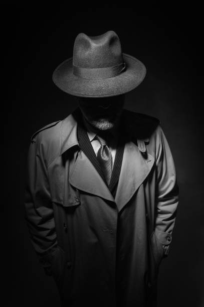 Noir movie character Man posing in the dark with a fedora hat and a trench coat, 1950s noir film style character gangster photos stock pictures, royalty-free photos & images