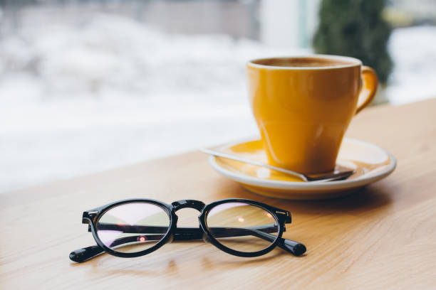 Yellow coffee Cup on the table and glasses in the coffee shop by the window. Selective focus. Toning.