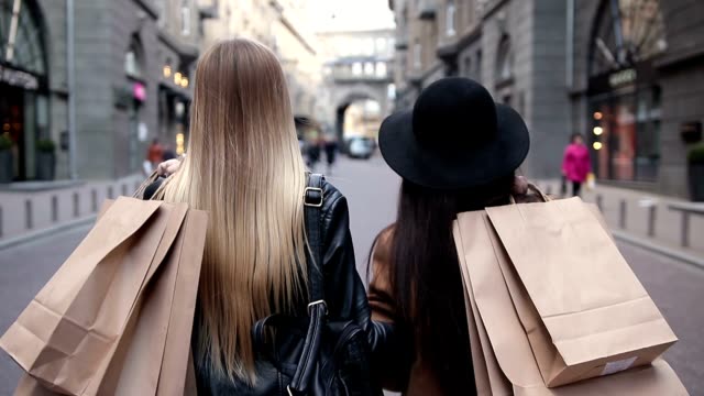 Back view of two walking women with shopping bags