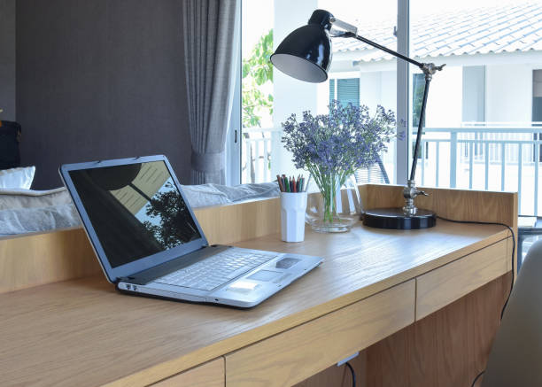 istock wooden table with computer notebook,pencil,lamp and flowers vase in modern working area 669223308