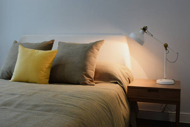 istock Cozy bedroom interior with pillows and white reading lamp on bedside table 669224420