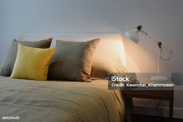 Cozy Bedroom Interior With Pillows And White Reading Lamp On Bedside Table Stock Photo - Download Image Now