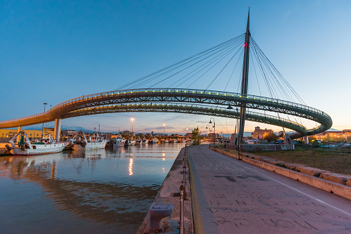 Pescara, Italy - 7 April 2017 - Urban landscape with the 'Ponte del Mare' monumental bridge at the dusk, in the canal and port of Pescara city, Abruzzo region