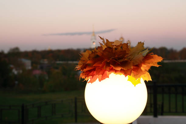 Fall in city. Autumn leaves wreath on glowing street lamp