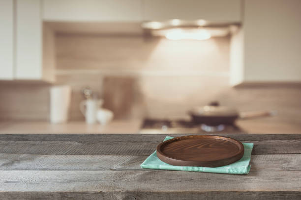 istock Blurred and abstract background. Empty wooden tabletop with tray and defocused modern kitchen background for display or montage your products. 669250506
