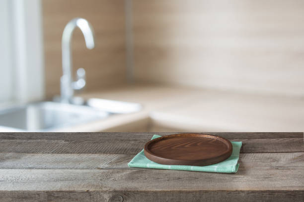 istock Blurred and abstract background. Empty wooden tabletop with tray and defocused modern kitchen background for display or montage your products. 669250510