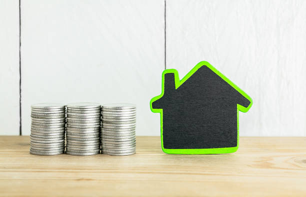 istock Stack of coins with house shaped on wood table over white background , saving for house concept 669254566