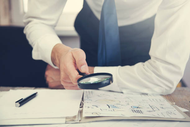 istock Businessman looking through a magnifying glass to documents 669256782