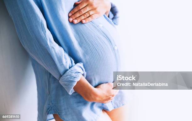 Pregnant Woman Holds Hands On Belly At Home Interiors Stock Photo - Download Image Now