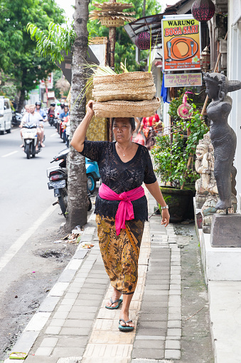UBUD, INDONESIA - MARCH 2: Senior woman carrying basket on the head on March 2, 2016 in Ubud, Indonesia.