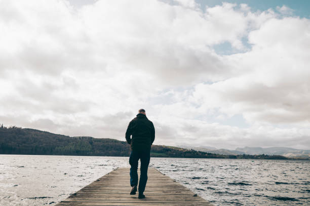 istock Man walking along a wooden jetty over a lake. 669305368