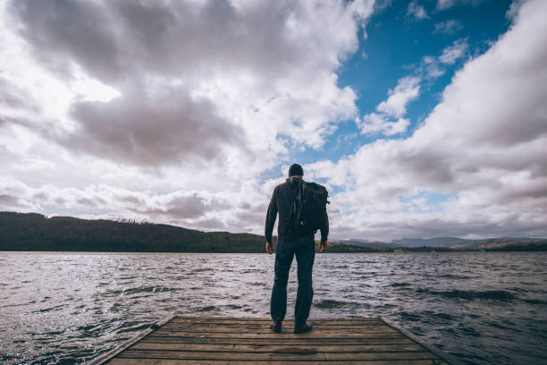 istock Man stood at the end of a jetty overlooking a lake. 669305392
