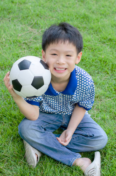 istock Young boy with ball in grass field 669313304