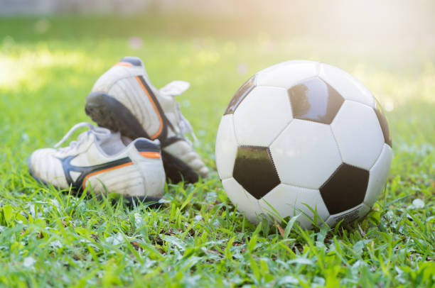 istock football on green grass and stud shoe with sun light 669323714
