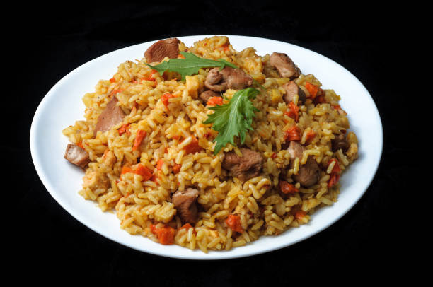 meat with rice and vegetables in white plate isolated on black
