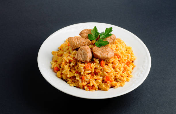 istock rice with meat and vegetables on a white plate. Pilaf isolated on gray background 669339178