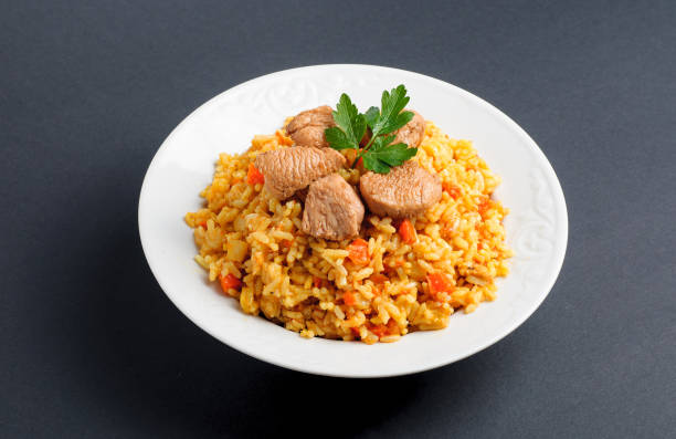 istock rice with meat and vegetables on a white plate. Pilaf isolated on gray background 669339184