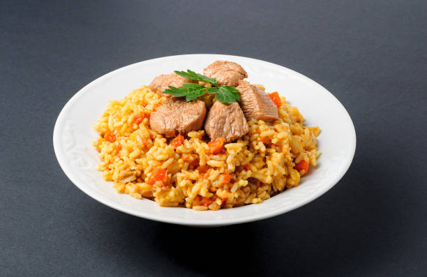 istock Fragrant Pilau. Pilaf, fried rice with meat and vegetables on a white plate. Isolated on gray. 669339256