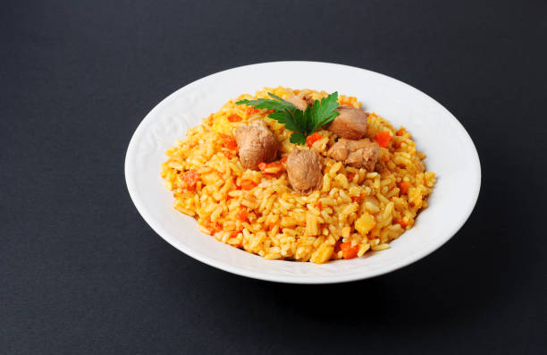 istock Fragrant pilaf with meat and vegetables top view on a plate. Isolated on black. 669339428
