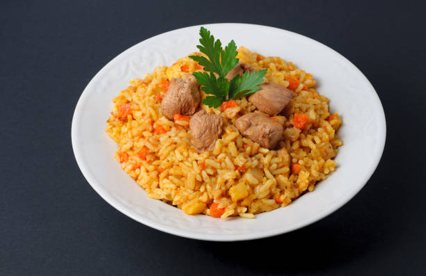 istock Fragrant pilaf with meat and vegetables top view on a plate. Isolated on black. 669339432