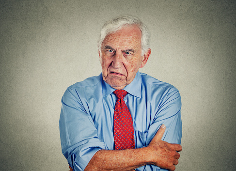 Portrait of unhappy grumpy pissed off senior mature man isolated on gray wall background. Negative human emotions, face expression feelings