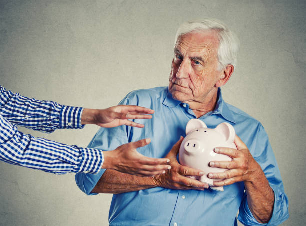 senior man grandfather holding piggy bank looking suspicious trying to protect his savings from being stolen Closeup portrait senior man grandfather holding piggy bank looking suspicious trying to protect his savings from being stolen isolated on gray wall background. Financial fraud concept "n belongings photos stock pictures, royalty-free photos & images
