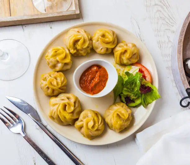 Nepalese traditional dumpling momos served with tomato chatni and fresh salad.