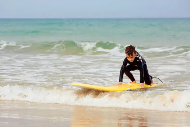 Photo of Little boy with surf board learning surfing