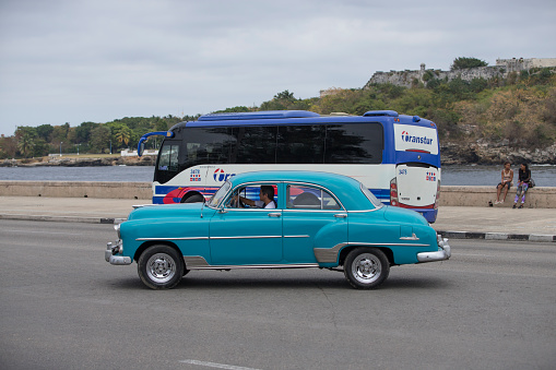 Havana, Cuba-January 28, 2017:Vintage cars are driving on the street. Incidental people on the background.