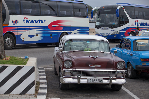 Havana, Cuba-January 28, 2017:A brown color Vintage car is driving on the street. A tourist bus on the background.