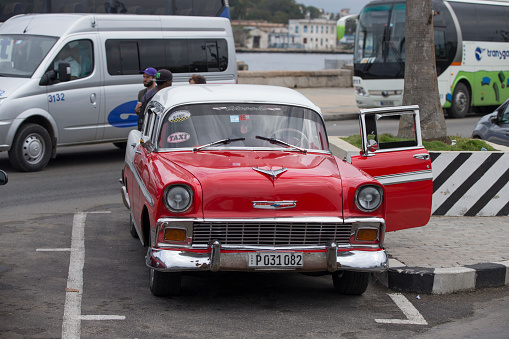 Havana, Cuba-January 28, 2017: A red Vintage car is parking on the street. Incidental people on the background.
