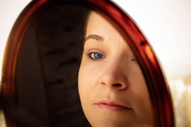 Portrait of a woman with long dark hair and expresive eyes looking at the camera, Coffee bar in Slovenia, Europe. Blond hair in the foreground, young man in the background. Nikon D800, full frame, XXXL.