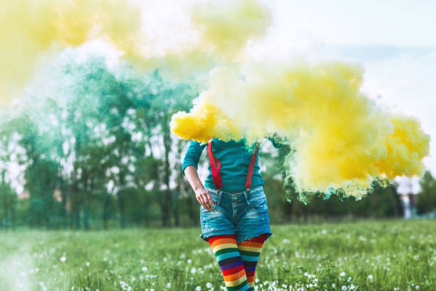 istock Young woman in a park with yellow smoke 669374508