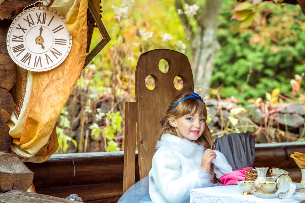 uma menina linda segurando o chapéu do cilindro com orelhas como um coelho nas mãos na mesa - little girls alice in wonderland child fairy tale - fotografias e filmes do acervo