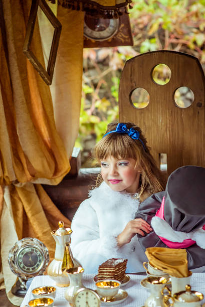 uma menina linda segurando o chapéu do cilindro com orelhas como um coelho nas mãos na mesa - little girls alice in wonderland child fairy tale - fotografias e filmes do acervo