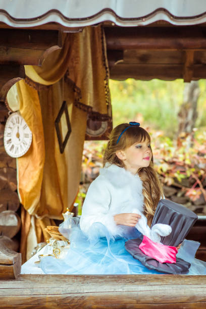 uma menina linda segurando o chapéu do cilindro com orelhas como um coelho nas mãos na mesa - little girls alice in wonderland child fairy tale - fotografias e filmes do acervo