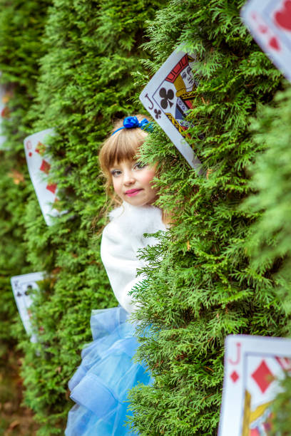 uma menina linda em um vestido longo azul olhando debaixo das árvores de abeto - little girls alice in wonderland child fairy tale - fotografias e filmes do acervo