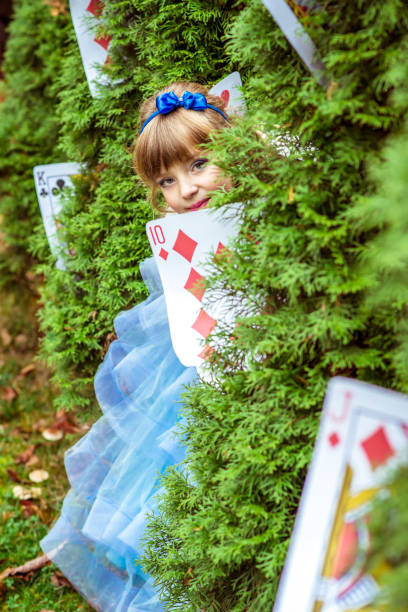 uma menina linda em um vestido longo azul olhando debaixo das árvores de abeto - little girls alice in wonderland child fairy tale - fotografias e filmes do acervo