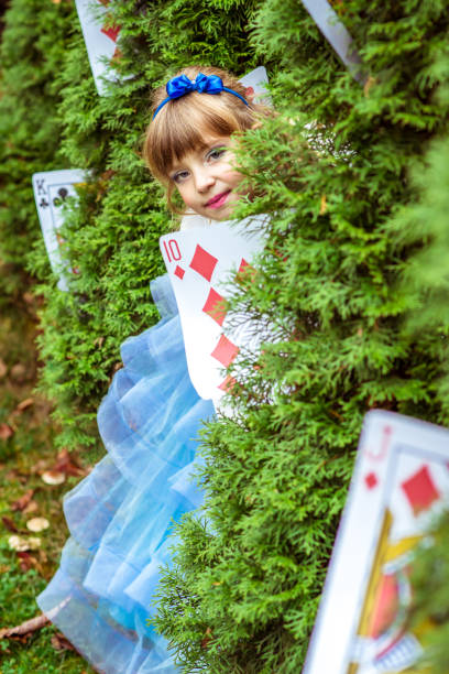 uma menina linda em um vestido longo azul olhando debaixo das árvores de abeto - little girls alice in wonderland child fairy tale - fotografias e filmes do acervo